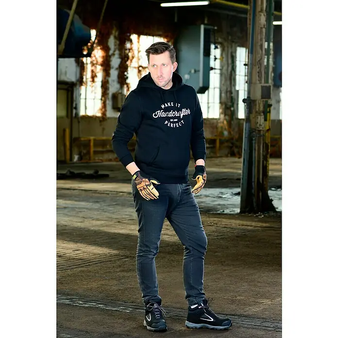 Mechanix Wear Arbeitshandschuhe Durahide M-Pact - L, Braun - Ein Mann trägt einen schwarzen "Make it Handcrafter Perfect" Hoodie, Jeans und Sicherheitsschuhe in einer Industrieumgebung.