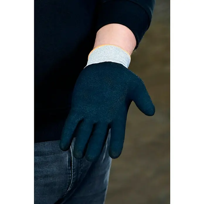 OX-ON Arbeitshandschuhe Recycle Comfort 16302 - Grau, 10 - Nahaufnahme eines Mannes mit einem schwarzen Arbeitshandschuh mit grauem Bündchen und Jeans.