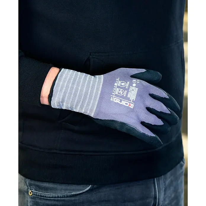 Guide Arbeitshandschuhe 577 - Grau/Schwarz, 11 - Nahaufnahme eines Mannes, der graue GUIDE Arbeitshandschuhe mit schwarzen Fingerspitzen und Handflächen trägt.