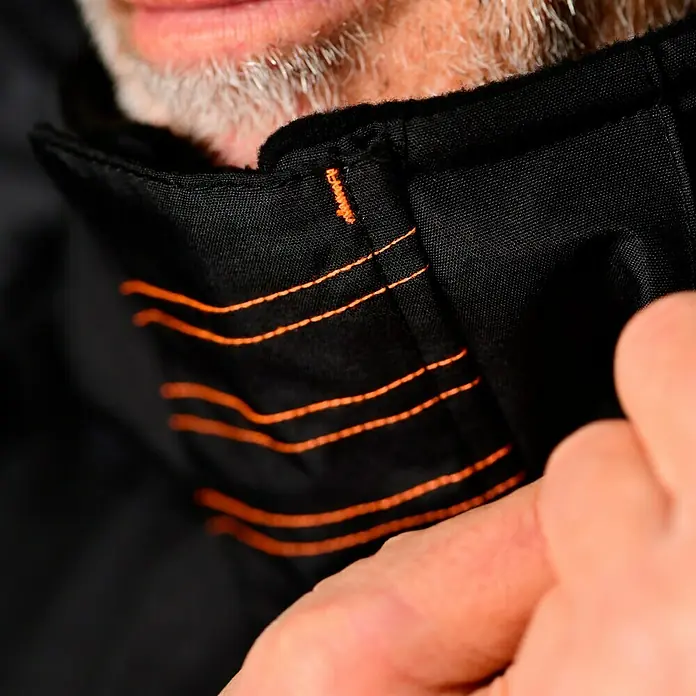 L.Brador Winterjacke 2190P - Schwarz, XXL - Nahaufnahme einer schwarzen Jacke mit orangefarbenen Ziernähten, die das Kleidungsstück hervorheben und einen stilvollen Akzent setzen.