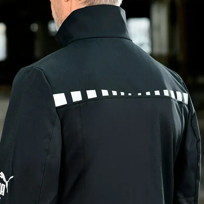 Puma Workwear Softshell-Jacke Champ - Carbon/Blau, M - Nahaufnahme einer schwarzen Puma Jacke mit reflektierenden Details.
