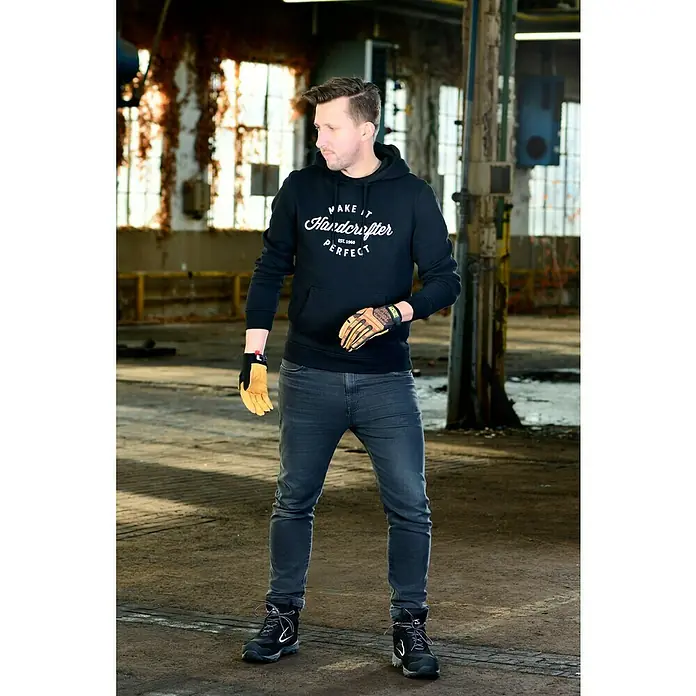 Mechanix Wear Arbeitshandschuhe Durahide M-Pact - L, Braun - Ein Mann in Arbeitskleidung mit Handschuhen und Stiefeln steht in einer Werkshalle. Er trägt einen Hoodie mit dem Aufdruck "Make it Handcrafter".