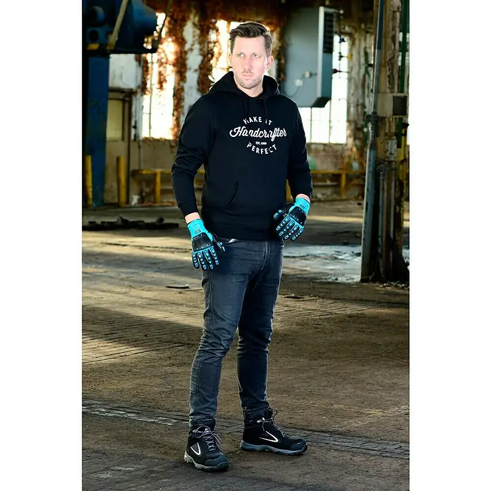 Hazet Arbeitshandschuhe - Blau/Schwarz, L - Ein Mann in Arbeitskleidung mit Handschuhen und Hoodie steht in einer Werkshalle.