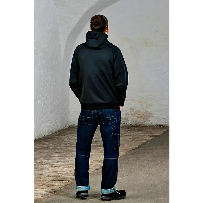 Bosch Professional Arbeitsjacke Hoodie GHH beheizbar - 2 -tlg., Akkuspannung: 12 V, XXL - Ein Mann mit schwarzer Kapuzenjacke, Jeans und schwarzen Schuhen steht mit dem Rücken zum Betrachter. Fokus liegt auf der Kleidung.