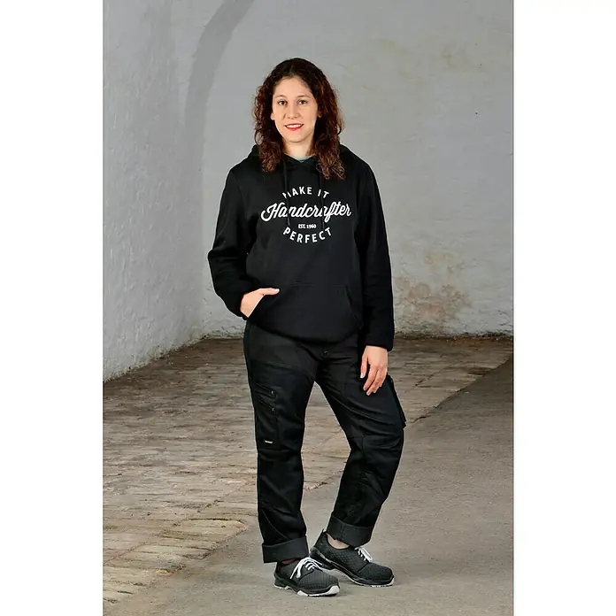 Steitz Secura Sicherheitshalbschuh GINGER - 38 - Eine Frau mit einem schwarzen "Handcrafter Perfect" Hoodie und Arbeitshosen.