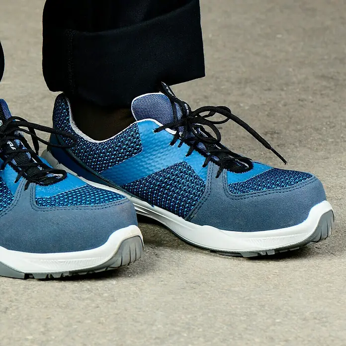 Steitz Secura Sicherheitshalbschuh ELLA - 41, Schutzklasse nach EN ISO 20345: S1 - Ein Paar blaue Arbeitsschuhe mit schwarzen Schnürsenkeln stehen auf einem grauen Betonboden. Bequeme und moderne Sicherheitsschuhe.