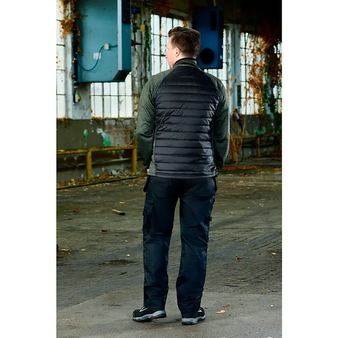 L.Brador Hybridjacke 6090P - Schwarz/Grün, S - Rückansicht eines Mannes in einer schwarzen Weste und Arbeitshose. Perfekt für den professionellen Einsatz.