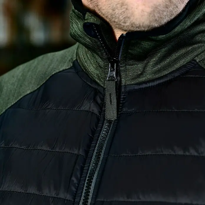 L.Brador Hybridjacke 6090P - Schwarz/Grün, S - Nahaufnahme einer schwarzen Steppjacke mit olivgrünem Kragen und Reißverschluss. Ideal für kühle Tage!