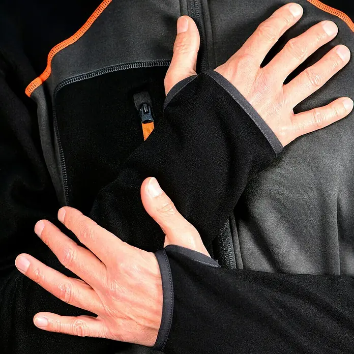L.Brador Fleecejacke 6195P - Schwarz/Grau, XL - Nahaufnahme einer Person in einer schwarzen Fleecejacke mit Daumenlöchern, die ihre Hände gekreuzt auf der Brust hält.