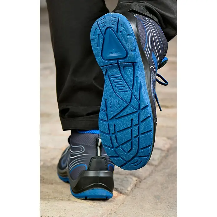 Safety Jogger Sicherheitsstiefel Flow S1P MID - 44, Schutzklasse nach EN ISO 20345: S1P, Schwarz, Blau - Nahaufnahme eines blauen Safety Master Schuhs mit markanter Profilsohle, getragen von einer Person in dunkler Hose.