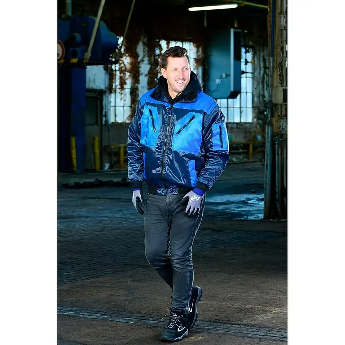 Guide Arbeitshandschuhe 3304 HP - Grau/Blau, 9 - Der Mann trägt eine stilvolle, marineblaue Arbeitsjacke mit blauen Akzenten, die ideal für den professionellen Einsatz ist. Die Jacke bietet Komfort und Schutz.