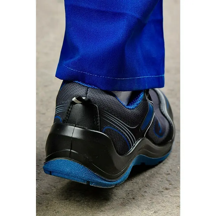 Safety Jogger Sicherheitshalbschuh Flow - 41, Schutzklasse nach EN ISO 20345: S1P, Blau, Schwarz - Nahaufnahme eines schwarzen und blauen Sicherheitsschuhs, getragen mit einer blauen Arbeitshose. Optimaler Schutz und Komfort im Arbeitsalltag.