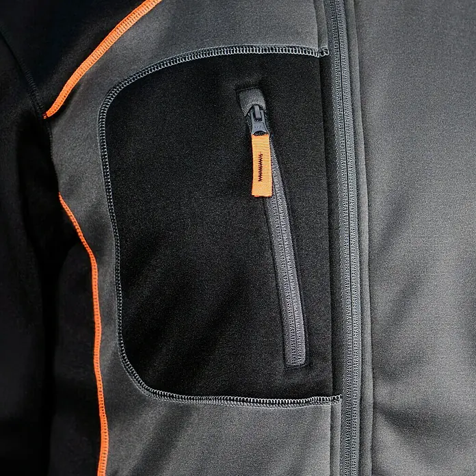 L.Brador Fleecejacke 6195P - Schwarz/Grau, XL - Detailaufnahme einer grauen Fleecejacke mit orangefarbenen Akzenten und Reißverschlusstasche. Ideal für Outdoor-Aktivitäten.