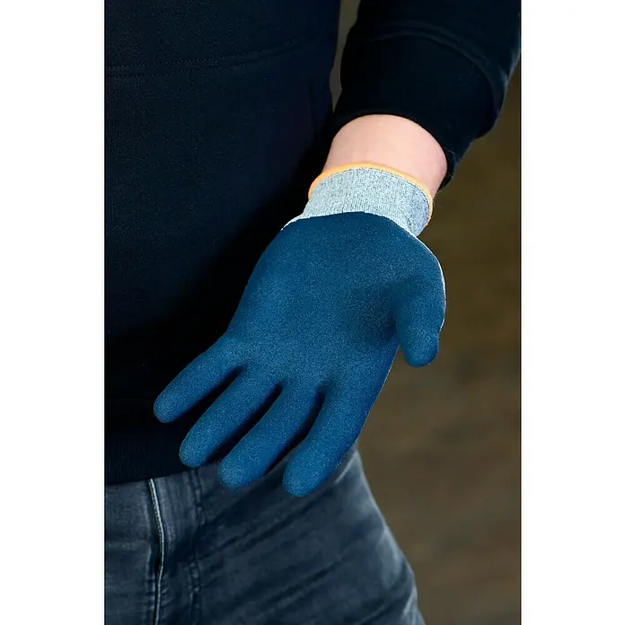 OX-ON Arbeitshandschuhe Recycle Basic 16003 - Grau, 8 - Nahaufnahme einer Hand mit einem blauen Schutzhandschuh mit grauem Bündchen und orangefarbener Kante, getragen von einer Person in Jeans und schwarzem Oberteil.