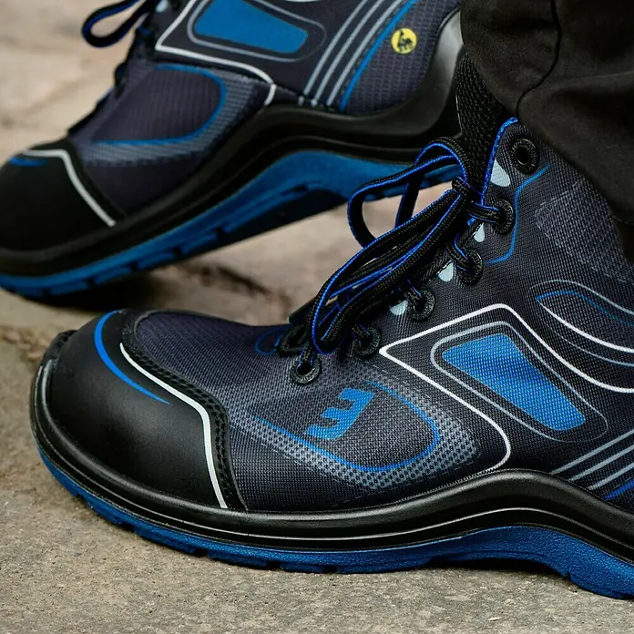Safety Jogger Sicherheitsstiefel Flow S1P MID - 44, Schutzklasse nach EN ISO 20345: S1P, Schwarz, Blau - Nahaufnahme von blauen und schwarzen Sicherheitsschuhen mit Schnürsenkeln auf einem Betonboden.