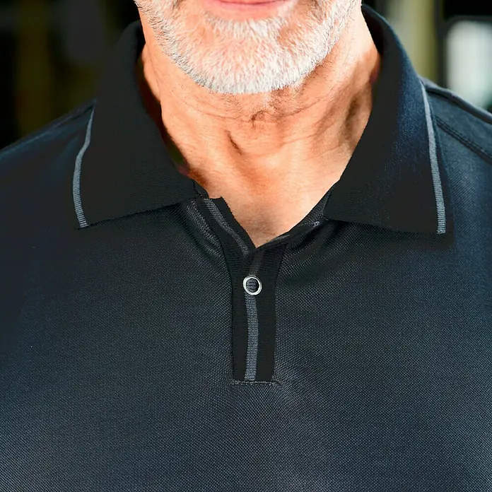 Puma Workwear Poloshirt Champ - Stahlgrau, Carbon, S - Nahaufnahme eines Mannes in einem schwarzen Poloshirt mit Knopf und grauen Akzenten. Das Shirt hat einen klassischen Schnitt und ist gut verarbeitet.