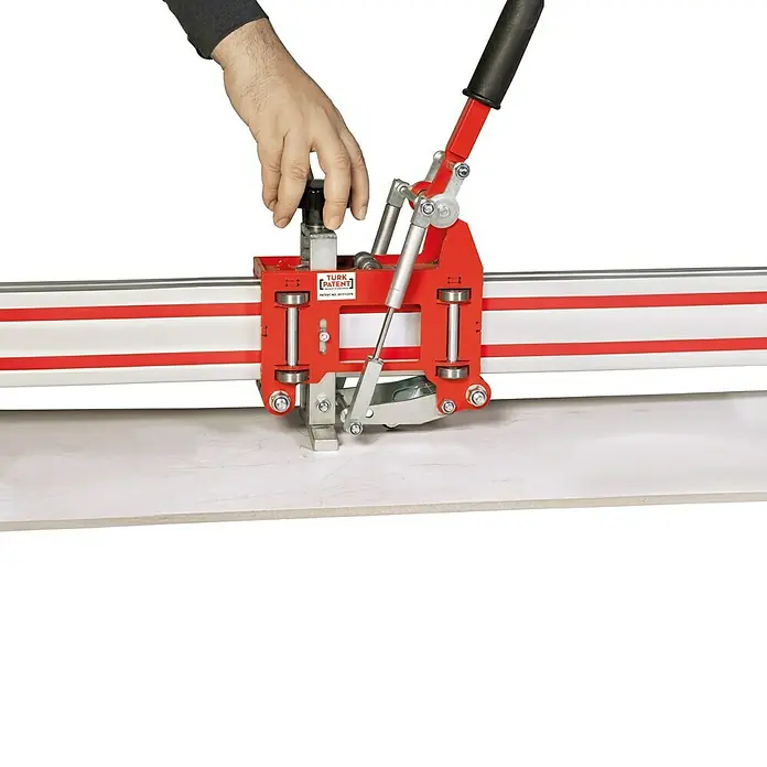 Heka Handfliesenschneider GiantCut 2600 - Max. Schnittlänge: 2.650 mm, Max. Fliesenstärke: 10 mm - Nahaufnahme eines Fliesenknackers in Aktion, der eine Fliese präzise teilt. Das rote Gerät steht im Fokus vor einem weißen Hintergrund.