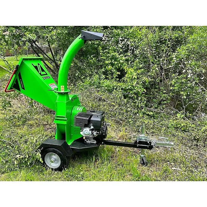 Zipper Benzin-Häcksler ZI-HAEK15000 - Max. Aststärke: 120 mm, 9 kW - Das Bild zeigt einen grünen Zipper ZI-HAE1500 Holzhäcksler im Freien, der für Gartenarbeiten und die Zerkleinerung von Ästen verwendet wird.