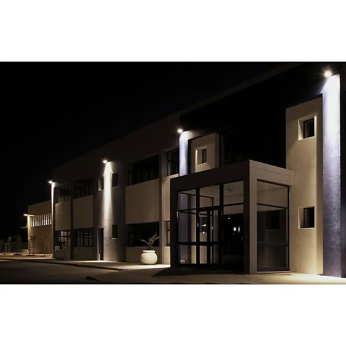 Philips Proyector LED Project Line - 150 W, Negro, Blanco neutro - Vista nocturna de un moderno edificio de oficinas con ventanas elegantes e iluminación exterior elegante que acentúa su arquitectura.