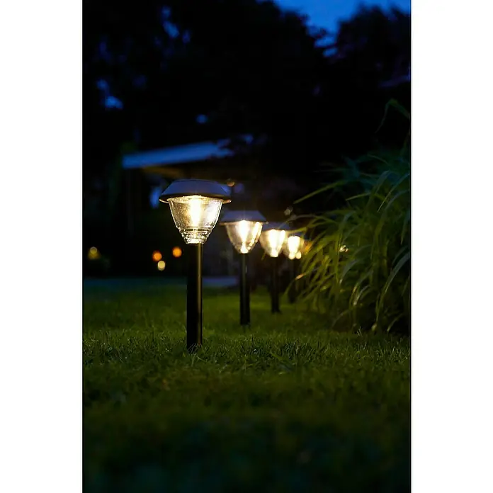 Luxform Solar-Erdspieß Kodiak - L x B x H: 11,5 x 11,5 x 43 cm, Anthrazit, IP44 - Reihe von leuchtenden Solarleuchten im Garten bei Nacht, die eine stimmungsvolle Beleuchtung erzeugen.
