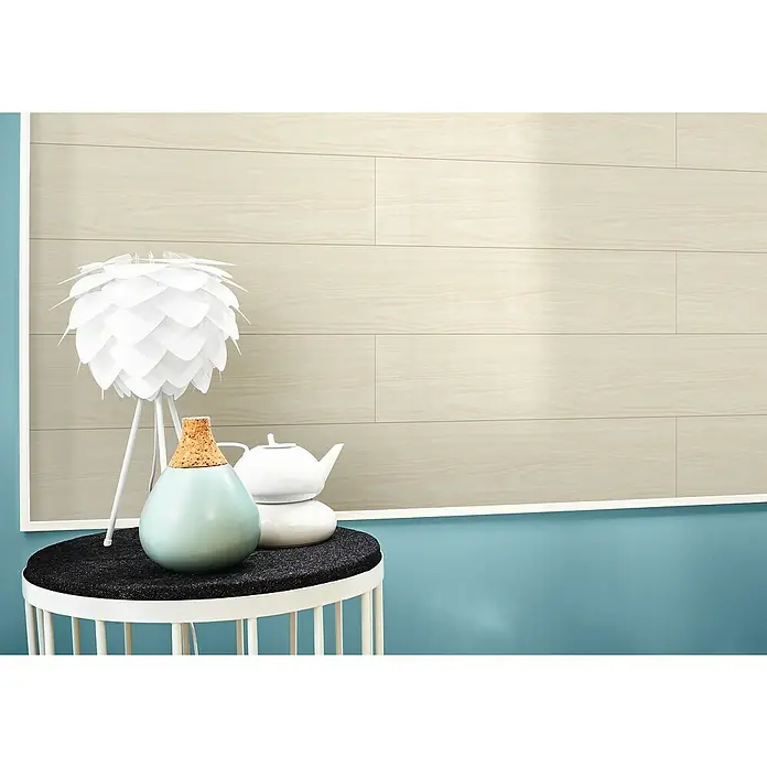 LOGOCLIC Variation Paneel Birne weiß - 2.000 x 154 x 10 mm - Nahaufnahme eines Tisches mit Dekoration, darunter eine Lampe mit Lampenschirm, eine Vase und eine Teekanne, vor einem Hintergrund aus Holzpaneelen.
