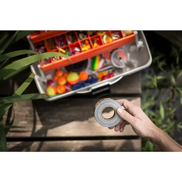 T-Rex Gewebeband - Schwarz, L x B: 9,1 m x 25 mm - Nahaufnahme von einer Rolle Panzertape mit einem Fischkasten im Hintergrund.