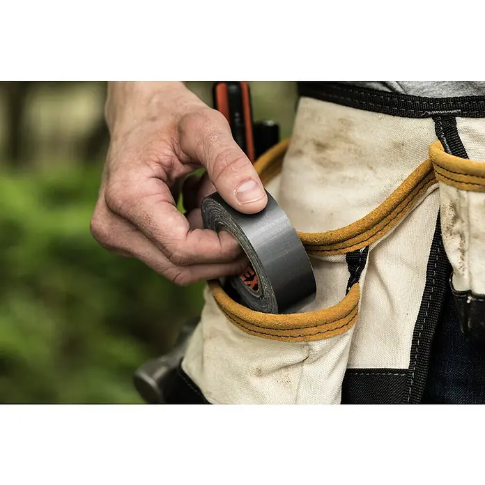 T-Rex Gewebeband - Schwarz, L x B: 9,1 m x 25 mm - Nahaufnahme von Bauarbeiter, der graues Isolierband in einer Werkzeugtasche verstaut, mit Fokus auf das graue Isolierband.