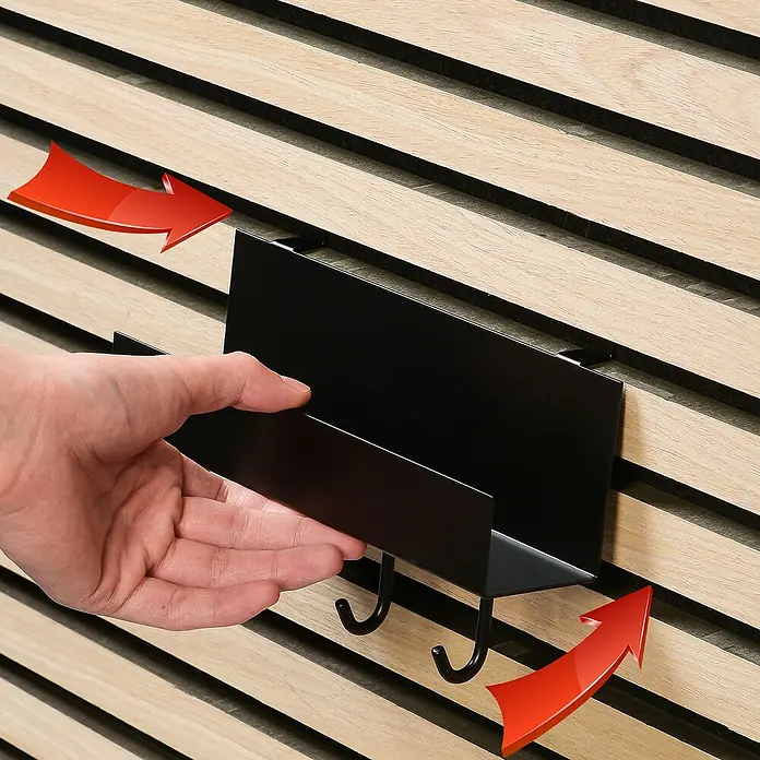 Millex Regal - L x B x H: 7 x 21,5 x 7 cm, Passend für: Akustikpaneele, Montageart: Einhängen - Nahaufnahme einer Hand, die eine schwarze Wandablage mit Haken an einer Holzpaneelwand befestigt.