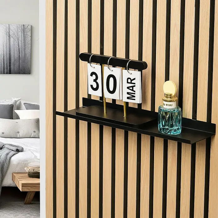 Millex Regal - L x B x H: 10 x 40 x 2,5 cm, Passend für: Akustikpaneele, Montageart: Einhängen - Nahaufnahme eines kleinen schwarzen Wandregals mit einem Kalender, der den 30. März anzeigt, und einer Flasche Parfüm.