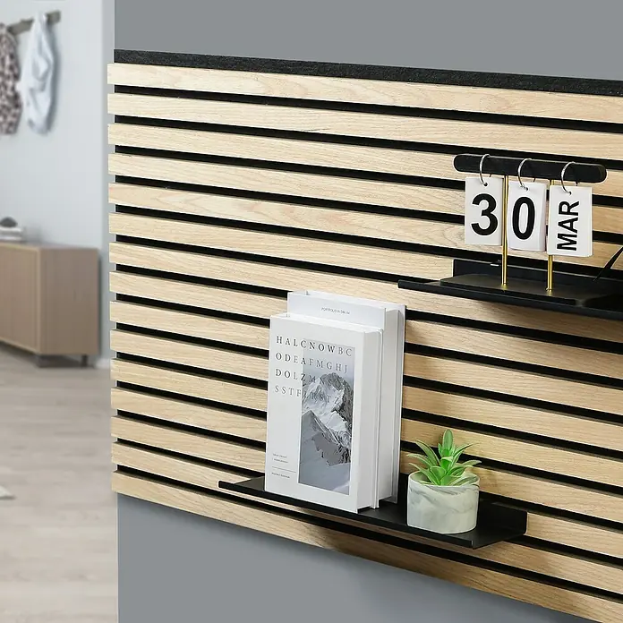 Millex Regal - L x B x H: 10 x 40 x 2,5 cm, Passend für: Akustikpaneele, Montageart: Einhängen - Nahaufnahme einer Lamellenwand mit zwei kleinen Regalen, auf denen ein Kalender, Bücher und eine Pflanze stehen.