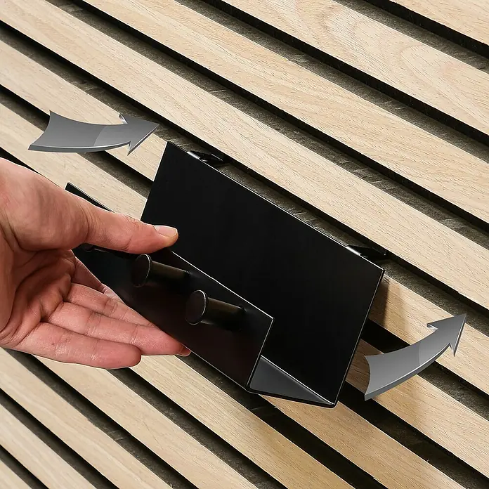Millex Regal - L x B x H: 5 x 21,5 x 7 cm, Passend für: Akustikpaneele, Montageart: Einhängen - Nahaufnahme einer Person, die einen schwarzen Wandhalter an einer Holzlattenwand befestigt, wobei Pfeile die Richtung der Bewegung anzeigen.