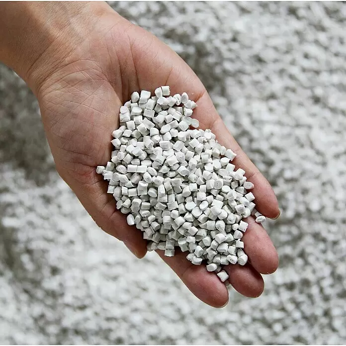 Ecopots Oslo Pflanztopf - Außenmaß (Ø x H): 55 x 48,5 cm, Kunststoff, Grau - Hand hält eine Handvoll kleiner, weißer Kunststoffpellets.
