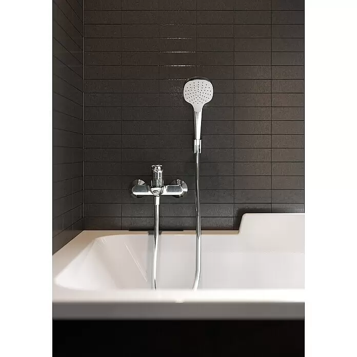 Hansgrohe Logis Grifo monomando de bañera - Profundidad del grifo: 194 mm, Cromo, Brillante - Bañera blanca con alcachofa de ducha y grifo cromados sobre azulejos oscuros en un baño moderno.