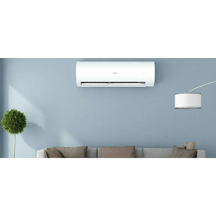Haier Aire acondicionado Inverter Perla - 3.500 W, 3.500 W, 35 m², Blanco - Elegante aire acondicionado Haier montado en una pared azul. Su diseño moderno se integra perfectamente en el espacio habitable, ofreciendo confort fresco.