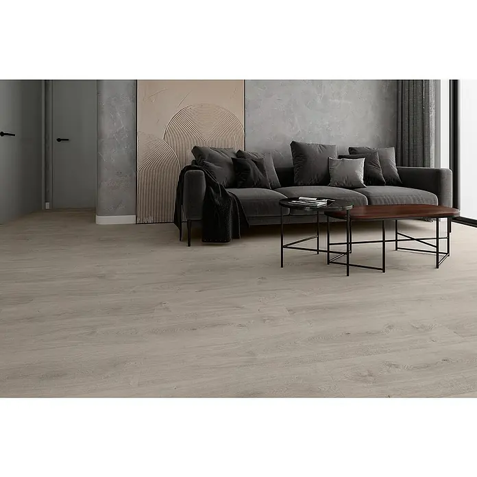 LOGOCLIC Laminado Roble Soho - 1.200 x 196 x 8 mm, Efecto madera campestre, AC4 - Sofá gris con cojines y manta, dos mesas de centro en la sala de estar. Un cuadro moderno y cortinas al fondo.