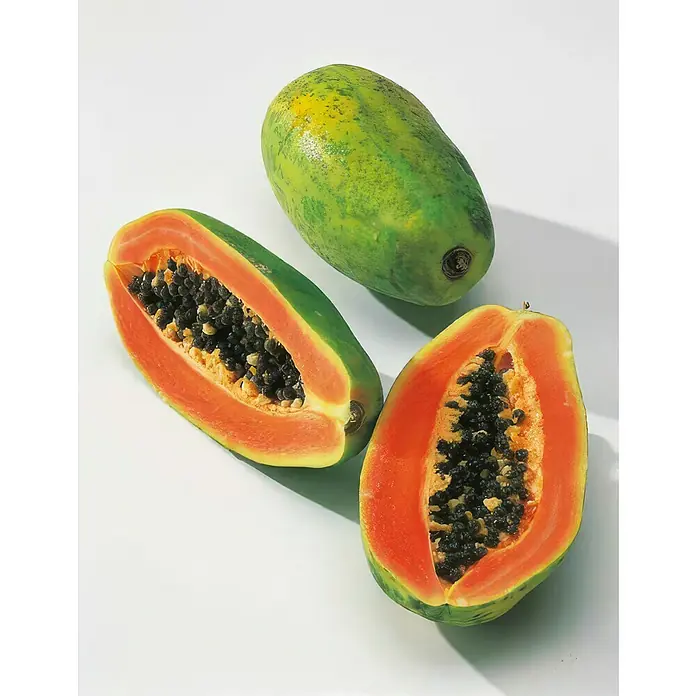 Obstbaum Bio Papaya - Carica papaya, Topfgröße: 19 cm - Nahaufnahme von zwei halbierten Papayas mit schwarzen Samen und einer ganzen grünen Papaya.