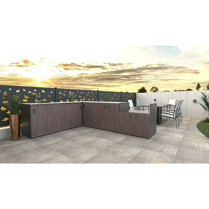 Bellano Living Outdoorküchen-Modul Grillelement - Walnuss, B x T x H: 90 x 63,4 x 92 cm - Moderne Außenküche mit braunen Schränken, Arbeitsplatte und Spüle vor dekorativem Sichtschutz mit Blattmuster und Essbereich im Hintergrund.