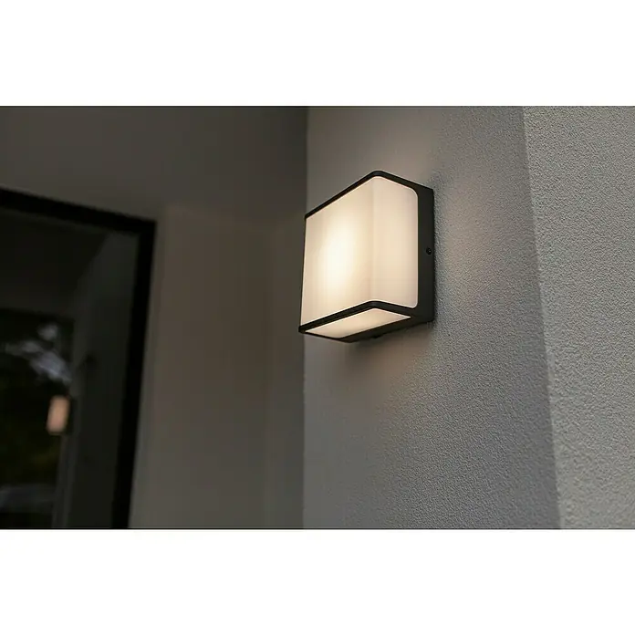 Lutec Doblo Aplique exterior LED Flat - 9 W, 8 x 15 x 15 cm, Negro mate, IP54 - Una lámpara de pared exterior cuadrada e iluminada con un marco oscuro está montada en una pared gris texturizada.