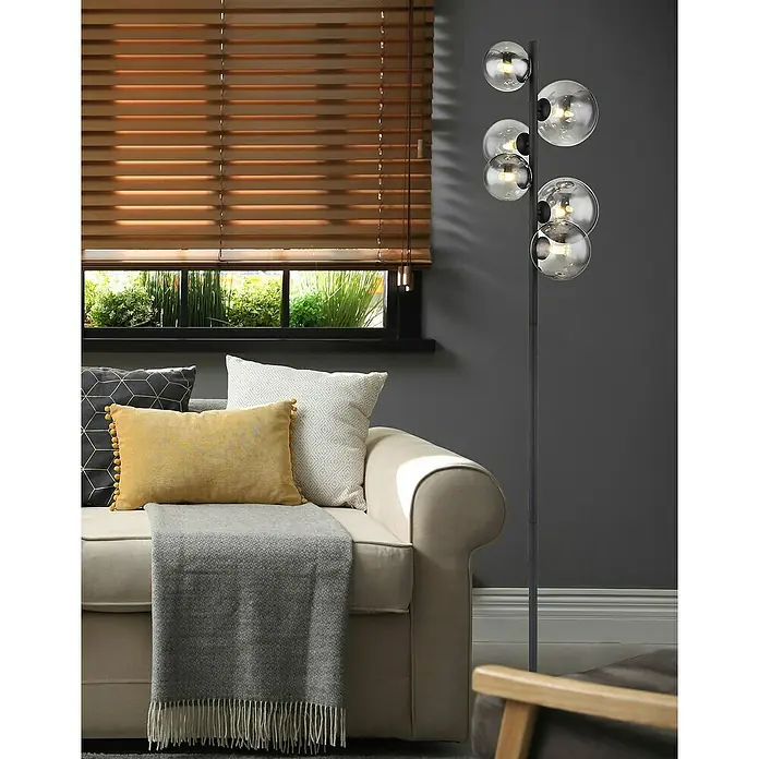 Globo Riha LED-Stehleuchte - 3,5 W, Höhe: 155 cm, Warmweiß - Elegante Stehlampe mit kugelförmigen Lampenschirmen und einladendem Wohnzimmerambiente mit Couch, Kissen und Holzjalousien im Hintergrund.