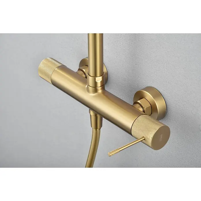 Imex Line Sistema de ducha - Con grifo monomando, Oro - Primer plano de una elegante grifería de ducha dorada montada en una pared gris, destacando un diseño de baño moderno.