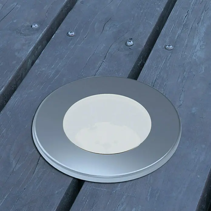Lutec Foco de jardín LED Hony Deck - 1 W, Plateado, IP67, LED - Primer plano de una luz LED redonda empotrada en una cubierta de madera, que proporciona iluminación ambiental.
