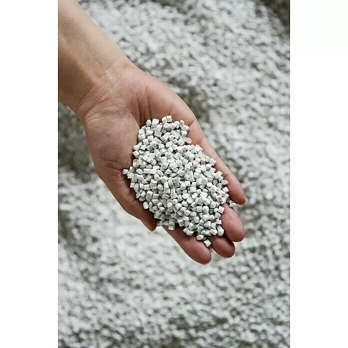 Ecopots Amsterdam Pflanztopf - Außenmaß (Ø x H): 40 x 354,5 cm, Kunststoff, Grau - Hand hält eine Handvoll weißer Kunststoffpellets, mit weiteren Pellets unscharf im Hintergrund.
