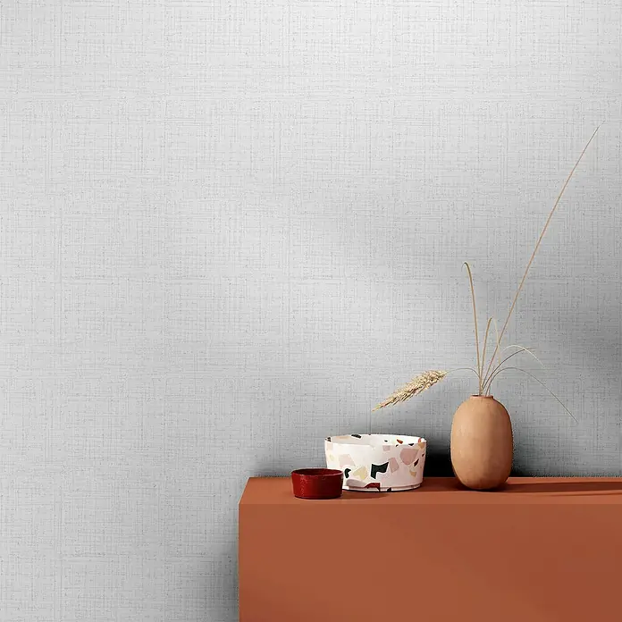 Marburg Heritage Vliestapete Vintage-Look - Weiß, Uni, 10,05 x 0,53 m - Nahaufnahme eines dekorierten Kaminsims mit Keramikvase, Schale und kleinem Behälter vor einer strukturierten Wand.