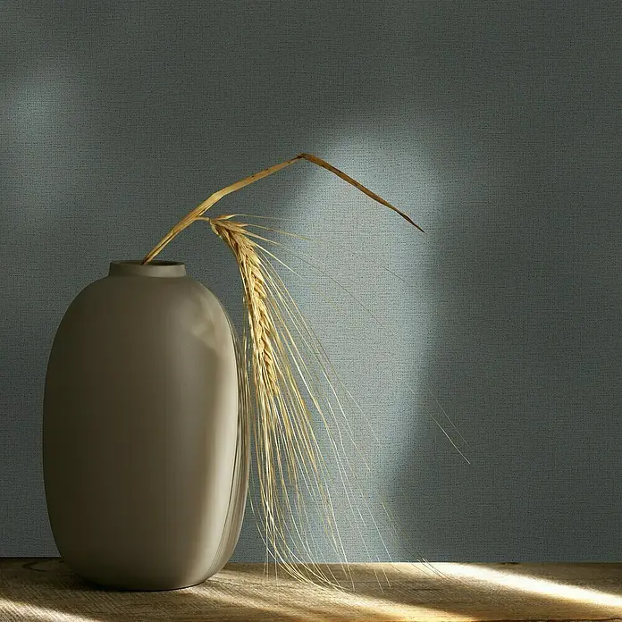 Marburg Struktura Vliestapete Jackie - Grau, Uni, 10,05 x 0,53 m - Ovale Vase mit Weizenhalm auf einem Holztisch, beleuchtet von einem sanften Lichtstrahl. Dekorative Inneneinrichtung mit natürlichem Flair.