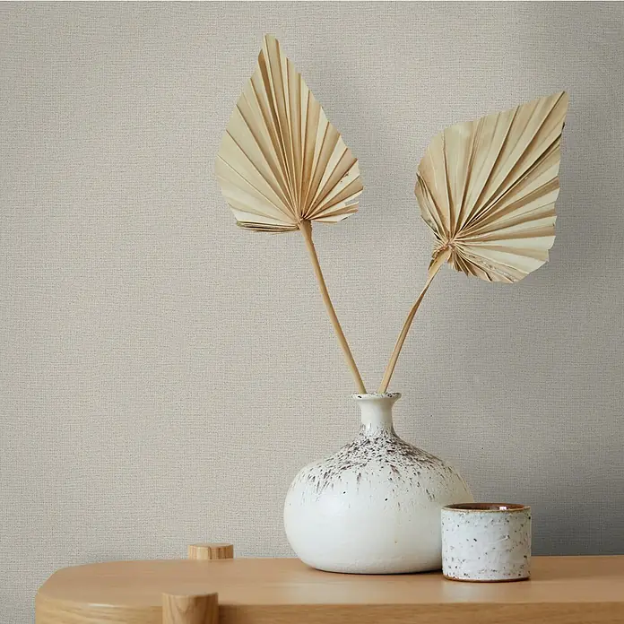 Marburg Struktura Vliestapete Jackie - Beigegrau, Uni, 10,05 x 0,53 m - Stillleben mit zwei Fächerpalmen in einer weißen Vase auf einem Holzregal, das minimalistische Dekor betont.