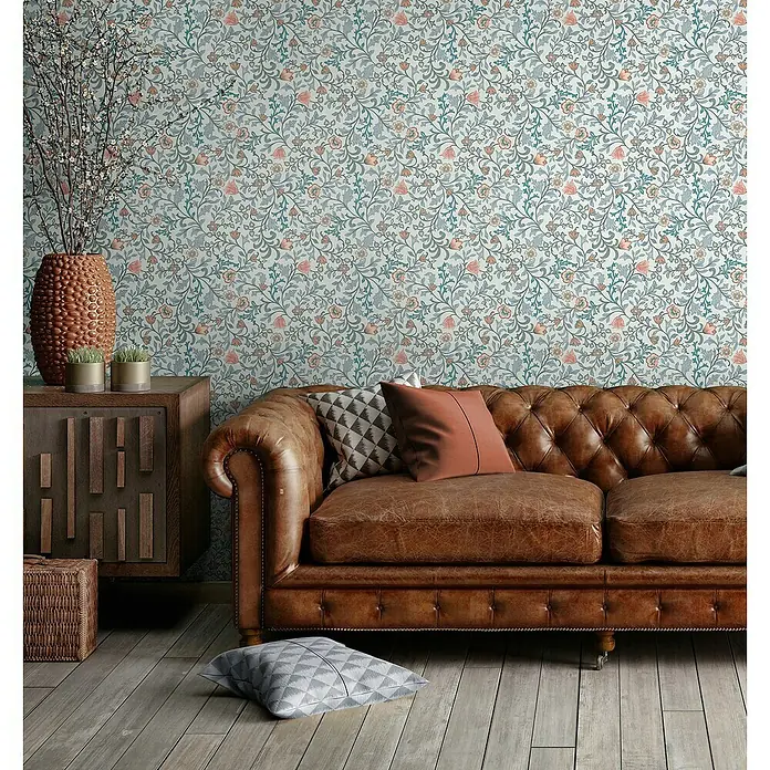 Marburg Heritage Vliestapete Blumenallover - Blau, Floral, 10,05 x 0,53 m - Gemütliches Wohnzimmer mit einem braunen Ledersofa, dekorativen Kissen und einer stilvollen Kommode vor einer floralen Tapete.