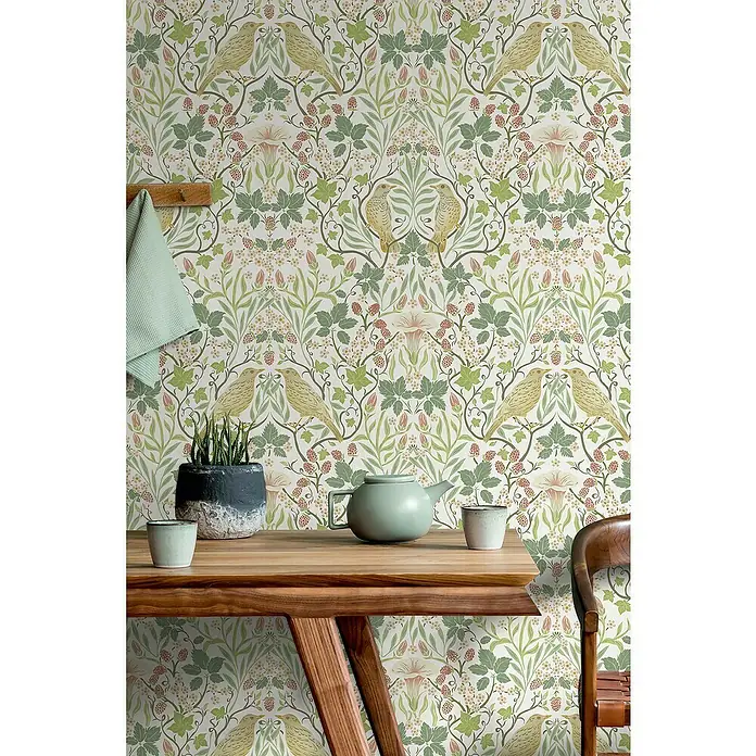 Marburg Heritage Vliestapete Tiere & Blumen - Weiß/Grün, Floral, 10,05 x 0,53 m - Ein Tisch mit einer Teekanne und Tassen vor einer Wandtapete mit einem Vogel- und Pflanzenmuster.