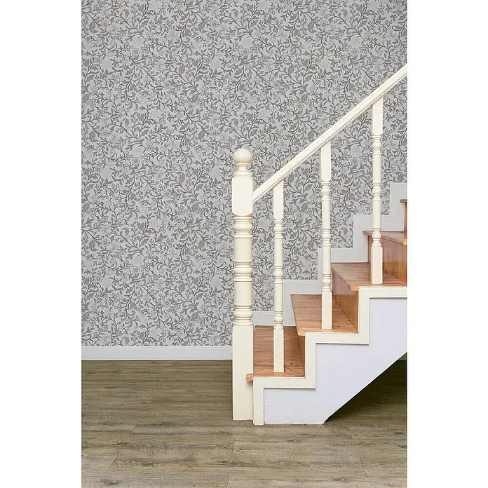 Marburg Heritage Vliestapete Blumenallover - Grau, Floral, 10,05 x 0,53 m - Detailansicht einer Treppe mit weißem Geländer vor einer floral gemusterten Wand, die die elegante Gestaltung des Treppenhauses hervorhebt.