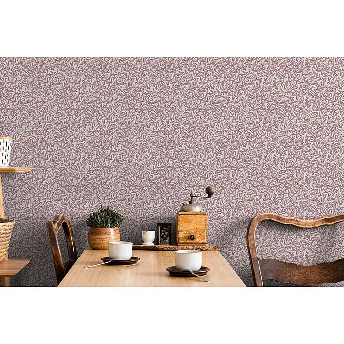 Marburg Heritage Vliestapete Blätterranken-Allover - Rot/Grau, Floral, 10,05 x 0,53 m - Tischgedeck mit Kaffeetassen, einer Pflanze und einer Kaffeemühle auf einem Holztisch vor einer Wand mit Blättertapete.