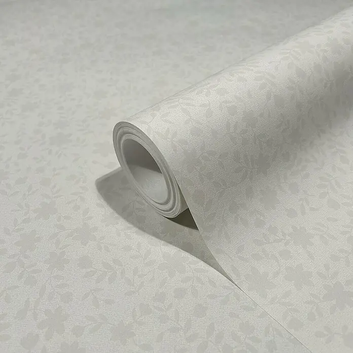 Marburg Heritage Vliestapete mit feinen Blättern - Beige, Floral, 10,05 x 0,53 m - Nahaufnahme einer Rolle weißer Tapete mit filigranem Blumenmuster, die eine subtile Eleganz und zeitlose Schönheit für jeden Raum verspricht.